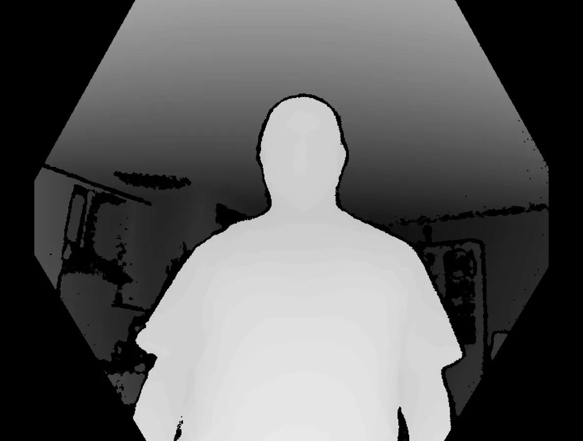 The depth frame of the same moment in greyscale: the man reads almost white because he is nearest the sensor, the ceiling above and the room behind him fall away through greys, and the pixels the sensor got no measurement for are pure black, including a ragged border along his silhouette