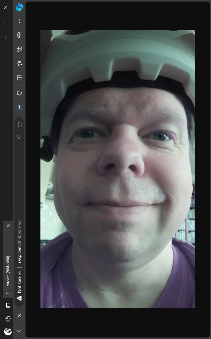 The browser control page playing the live 864x480 stream from the camera: a face under a helmet, filling the frame